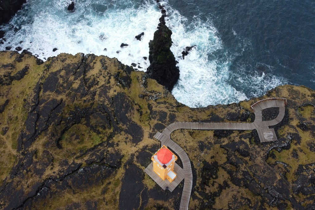 Svortuloft Lighthouse is a bright orange structure set high above the water in the Snaefellsnes Peninsula